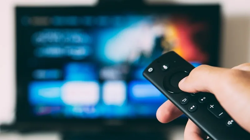 Television remote pointed at a screen showing a streaming app interface, representing IPTV live TV